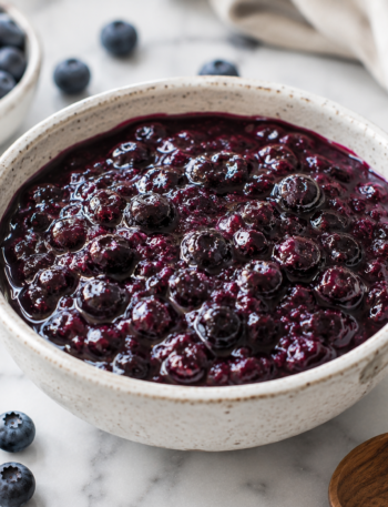 A bowl of homemade blueberry compote recipe made with fresh blueberries, served as a glossy fruit topping.