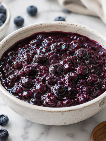 A bowl of homemade blueberry compote recipe made with fresh blueberries, served as a glossy fruit topping.