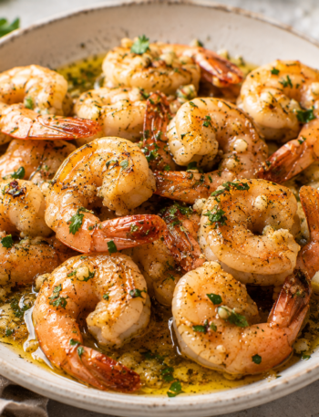 Garlic butter shrimp with lemon, parsley, and glossy garlic butter sauce served in a shallow bowl.