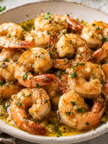 Garlic butter shrimp with lemon, parsley, and glossy garlic butter sauce served in a shallow bowl.