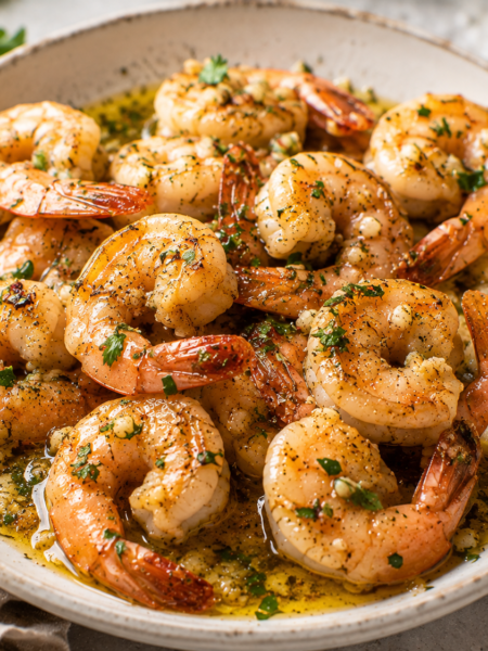Garlic butter shrimp with lemon, parsley, and glossy garlic butter sauce served in a shallow bowl.